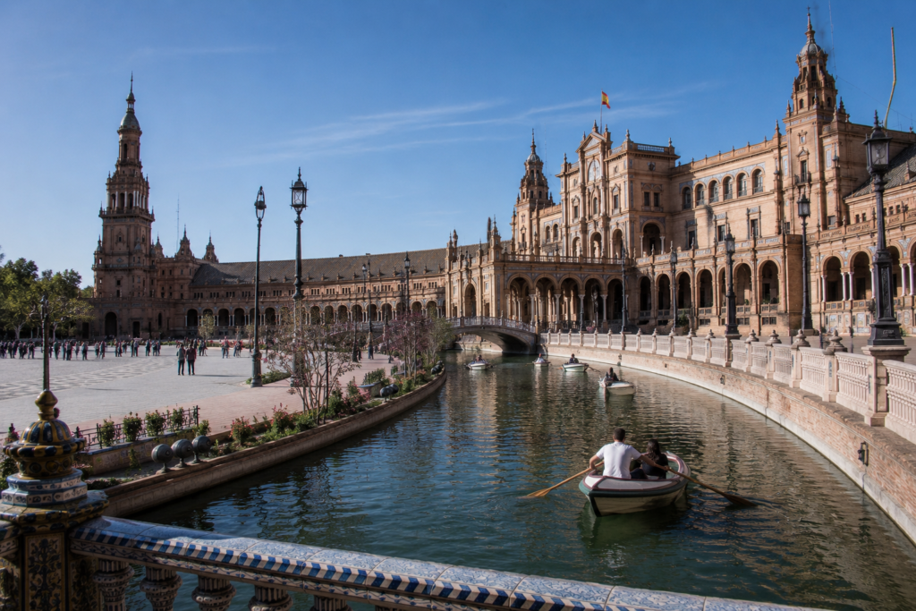 Panoramic view of Plaza de España in Seville, Spain, featuring the historic canal, elegant bridges, and beautiful Renaissance architecture on a sunny day